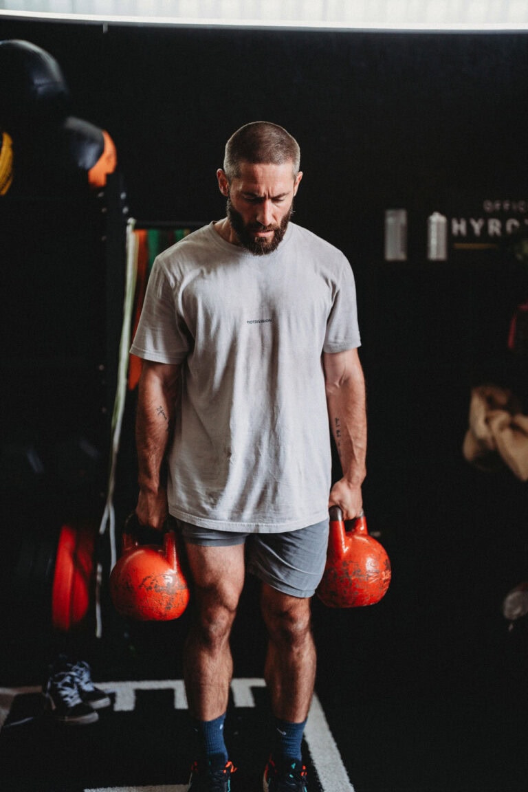 Arsen Halieiev doing a farmer's walk with kettlebells